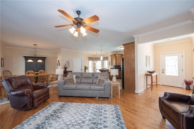 living area with baseboards, ceiling fan with notable chandelier, crown molding, and light wood finished floors