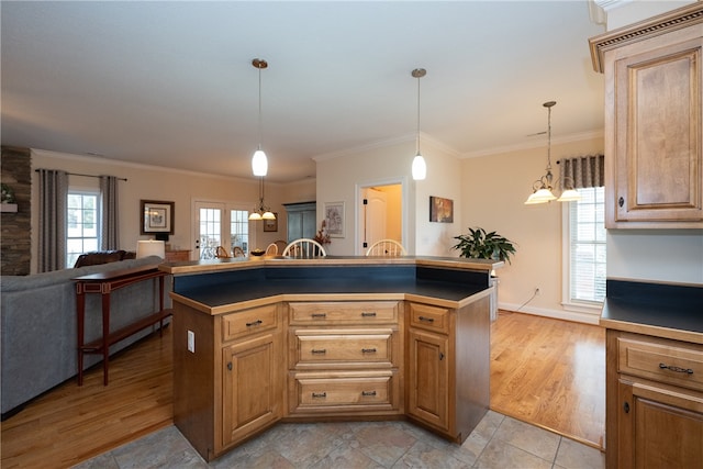 kitchen with a wealth of natural light, dark countertops, light wood-type flooring, and ornamental molding