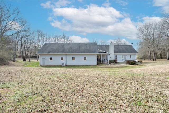 rear view of property featuring a yard and a chimney