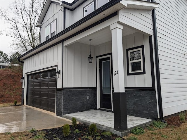 doorway to property with stone siding, board and batten siding, and an attached garage