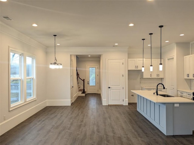 kitchen with dark wood-type flooring, white cabinets, visible vents, and a sink