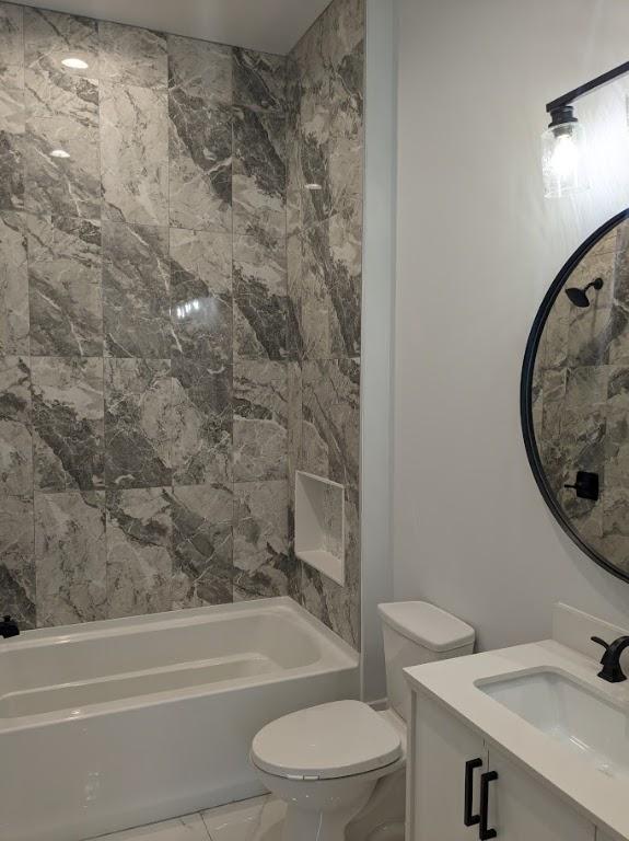 bathroom with marble finish floor, vanity, toilet, and shower / tub combination