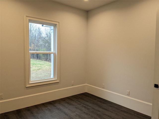 unfurnished room featuring dark wood-type flooring and baseboards