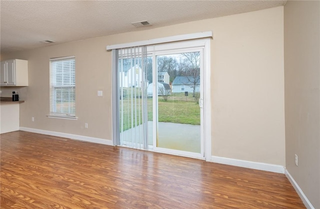 entryway featuring visible vents, a textured ceiling, baseboards, and wood finished floors