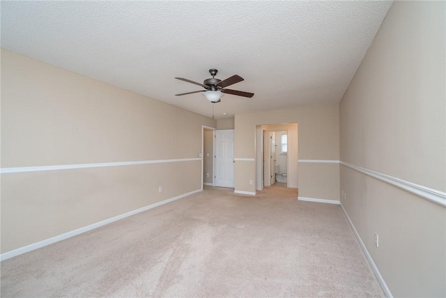 interior space with ceiling fan, light colored carpet, baseboards, and a textured ceiling