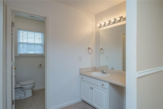 bathroom featuring toilet, vanity, and baseboards