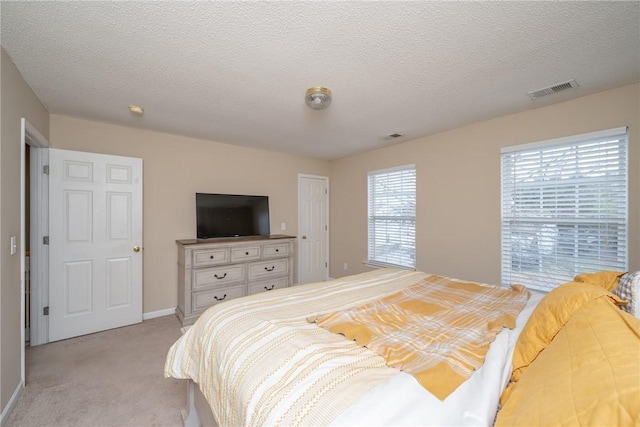 bedroom with visible vents, light carpet, a textured ceiling, and baseboards