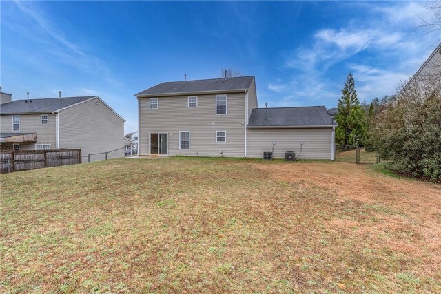 rear view of property with a lawn, fence, and central AC