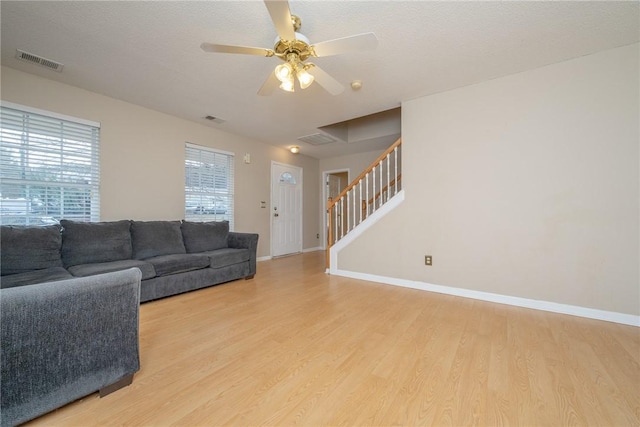 living area featuring light wood finished floors, visible vents, and stairway