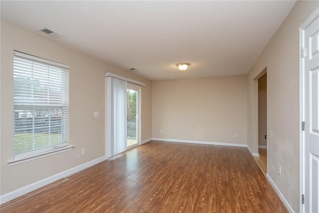 spare room featuring visible vents, baseboards, and wood finished floors