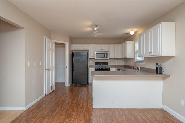 kitchen featuring black appliances, dark wood-style floors, a peninsula, and a sink