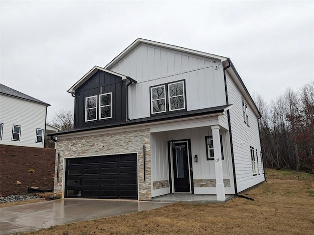 modern farmhouse style home with a front lawn, stone siding, board and batten siding, concrete driveway, and a garage