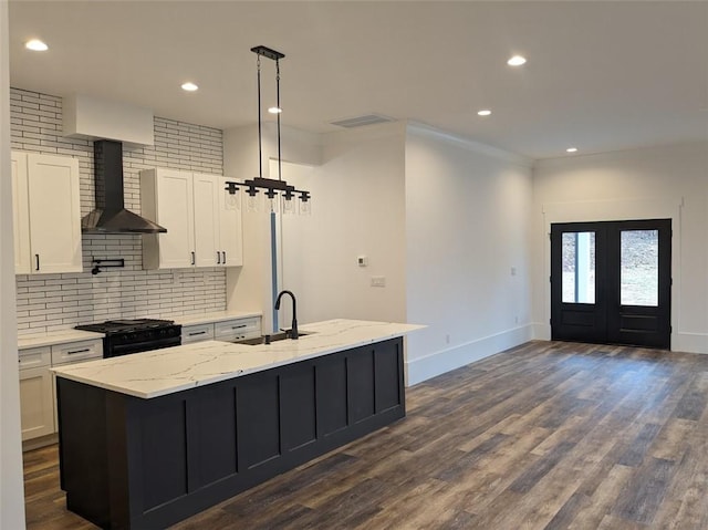 kitchen with black gas stove, dark wood-type flooring, wall chimney range hood, white cabinets, and a sink