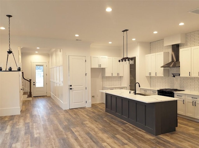 kitchen with black range with gas stovetop, dark wood-style flooring, wall chimney range hood, and a sink