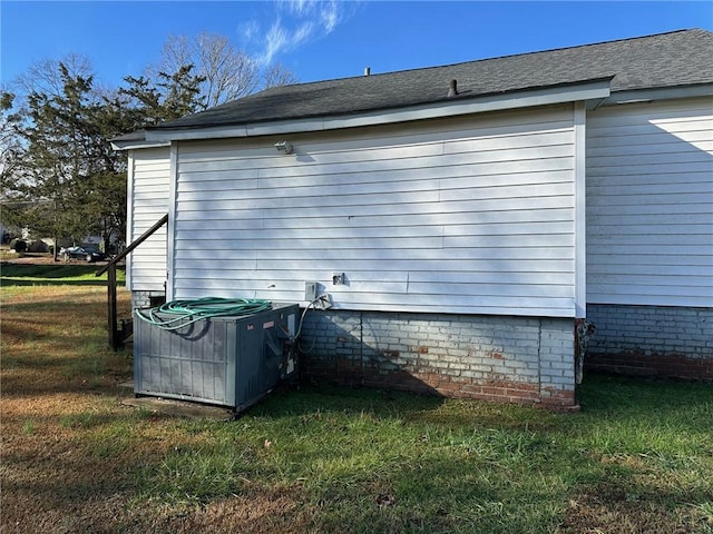 view of side of property featuring a lawn and central AC