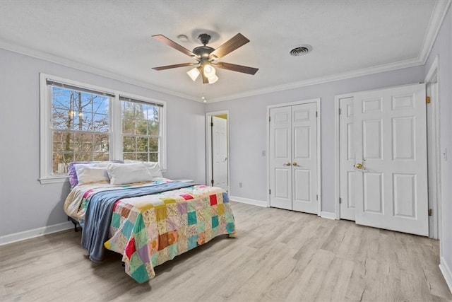 bedroom with visible vents, baseboards, ornamental molding, and light wood-style flooring