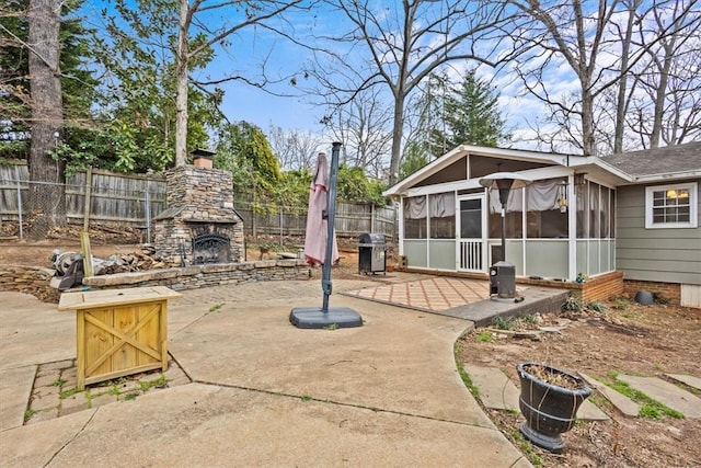 view of patio / terrace with grilling area, an outdoor stone fireplace, a sunroom, and fence