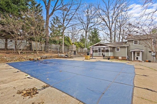 view of pool with a patio, fence, a fireplace, a sunroom, and a fenced in pool