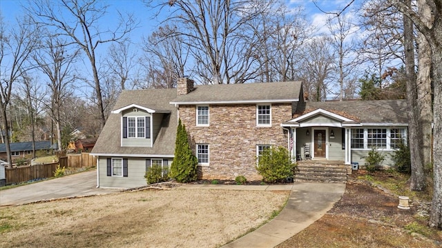 view of front of home featuring fence, a shingled roof, a chimney, a front lawn, and stone siding