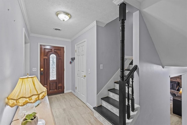 entryway with visible vents, a textured ceiling, wood finished floors, stairway, and crown molding