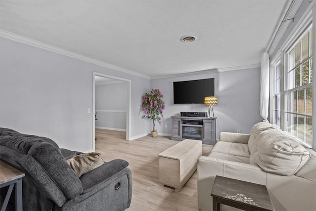 living room featuring baseboards, visible vents, light wood-type flooring, and ornamental molding