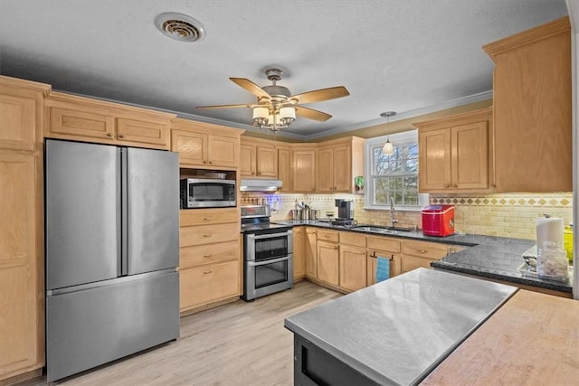 kitchen featuring visible vents, a sink, under cabinet range hood, stainless steel appliances, and light wood-style floors