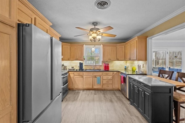 kitchen with light wood-style flooring, light brown cabinetry, a sink, appliances with stainless steel finishes, and crown molding