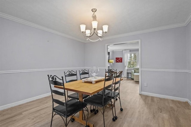 dining space featuring a notable chandelier, light wood-style flooring, crown molding, and baseboards