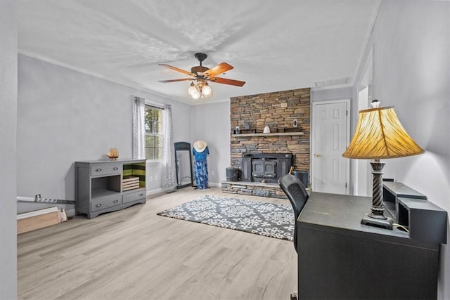 office with visible vents, baseboards, ornamental molding, a wood stove, and wood finished floors