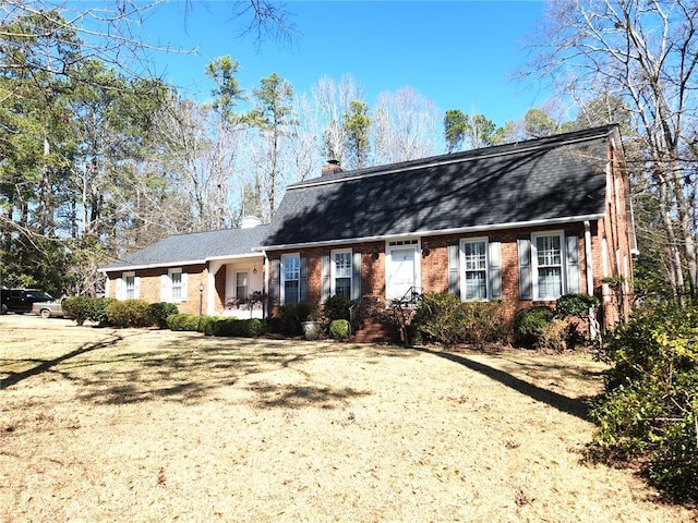 colonial inspired home with brick siding and a chimney