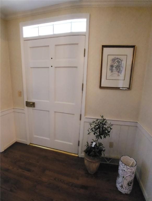 entrance foyer with ornamental molding, dark wood-style floors, and wainscoting