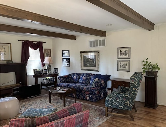 living room featuring beam ceiling, visible vents, ornamental molding, and wood finished floors