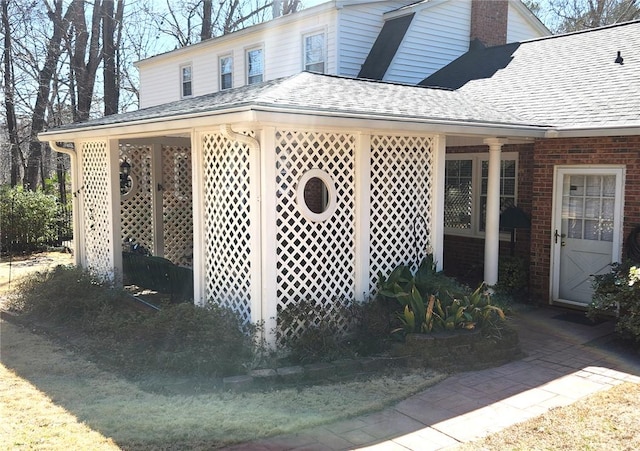 view of side of property featuring brick siding, roof with shingles, and a chimney