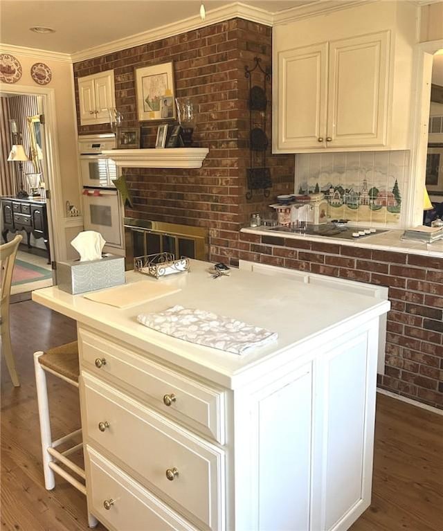 kitchen featuring double oven, light countertops, wood finished floors, and ornamental molding