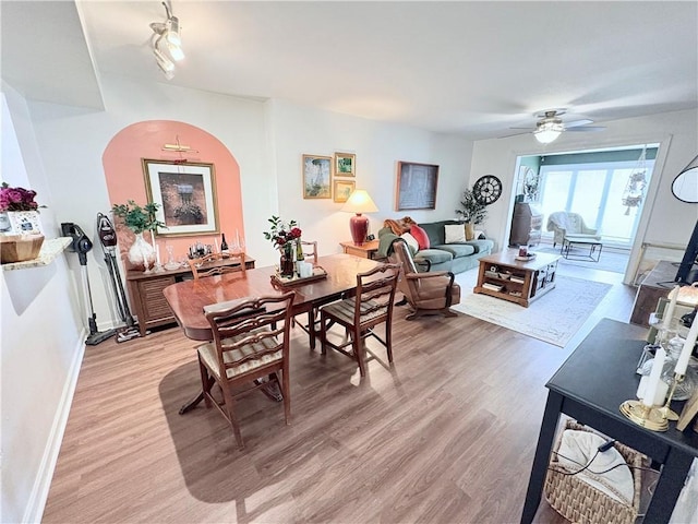 dining space featuring light wood-style flooring, a ceiling fan, and baseboards