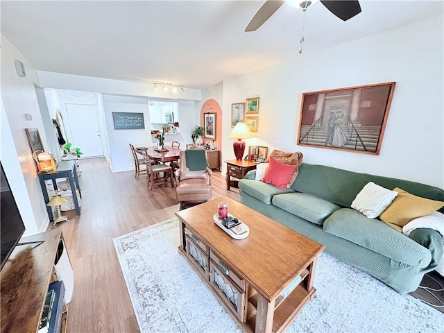 living room featuring arched walkways, baseboards, ceiling fan, and wood finished floors