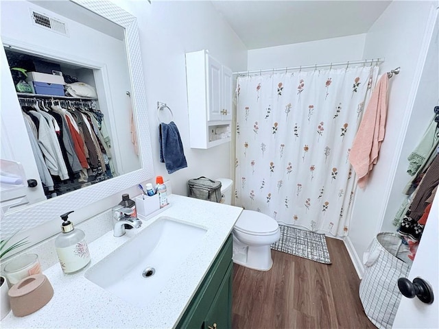 full bath featuring vanity, a shower with shower curtain, wood finished floors, and visible vents