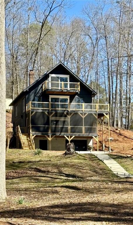 view of front of home featuring a balcony, an attached garage, a chimney, stairs, and concrete driveway