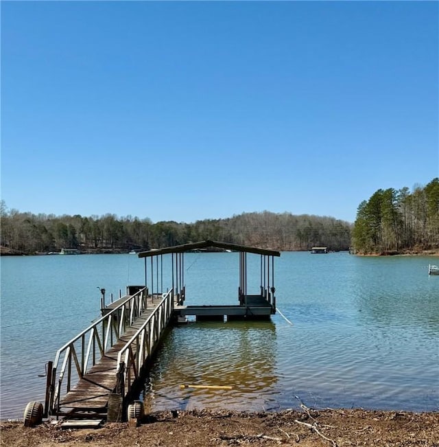 dock area featuring a wooded view and a water view