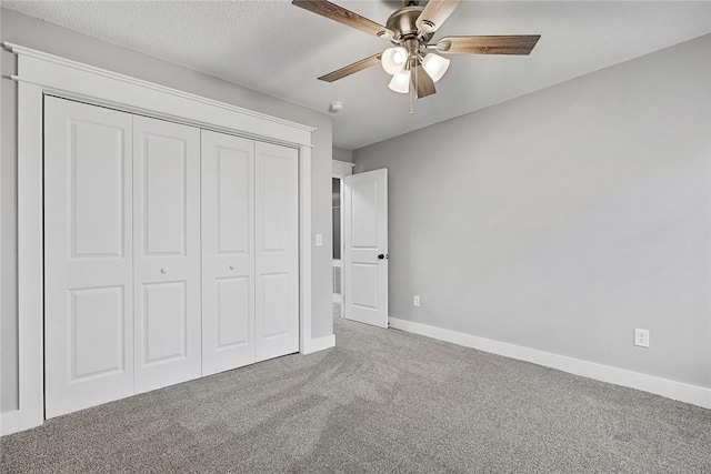 unfurnished bedroom with baseboards, carpet floors, a closet, a textured ceiling, and a ceiling fan