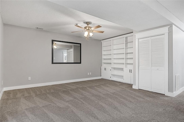 unfurnished bedroom featuring visible vents, a ceiling fan, a textured ceiling, carpet flooring, and baseboards