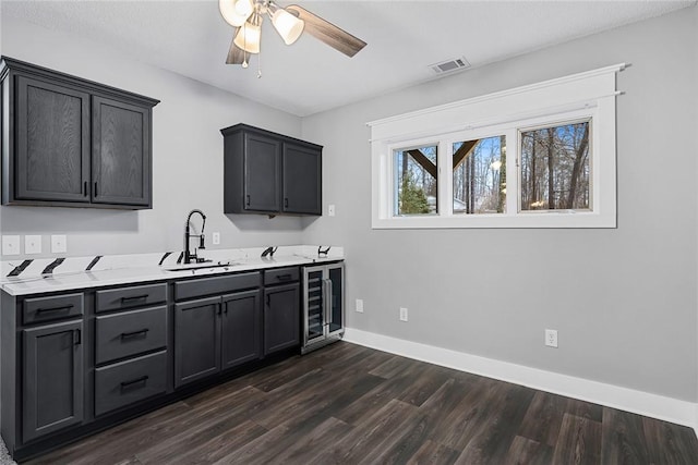 kitchen with visible vents, a sink, wine cooler, baseboards, and dark wood-style flooring