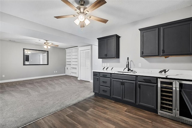 kitchen with wine cooler, dark carpet, light countertops, dark wood-style floors, and a sink