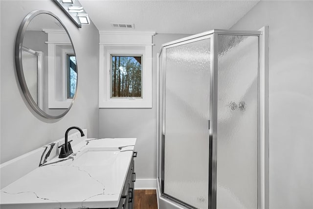 full bathroom featuring visible vents, a shower stall, vanity, wood finished floors, and a textured ceiling