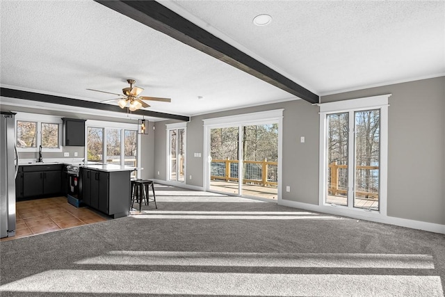 unfurnished living room featuring a sink, beamed ceiling, and a textured ceiling