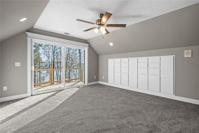 bonus room featuring visible vents, baseboards, dark carpet, vaulted ceiling, and a textured ceiling