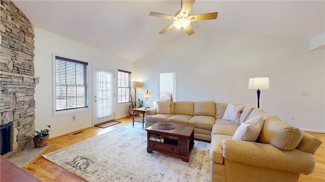 living room featuring ceiling fan, baseboards, light wood-style flooring, and a fireplace