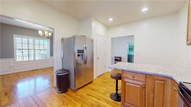 kitchen with a wainscoted wall, range with electric stovetop, light wood-style flooring, and stainless steel fridge with ice dispenser