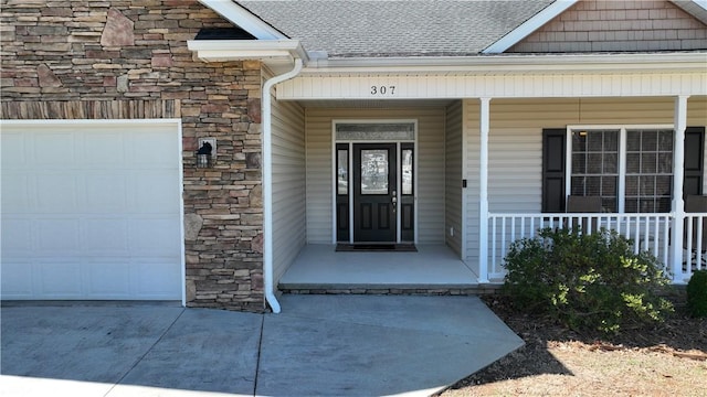 view of exterior entry featuring a porch, an attached garage, and stone siding