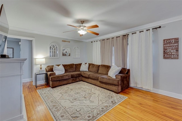 living room with light wood-type flooring, baseboards, ornamental molding, and a ceiling fan